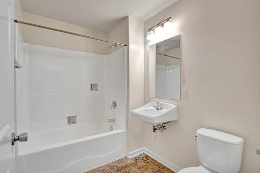 A white bathroom with a toilet, sink, and bathtub.