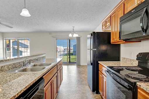 A kitchen with black appliances and granite countertops.