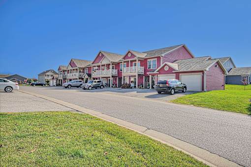 A row of houses with cars parked in front.