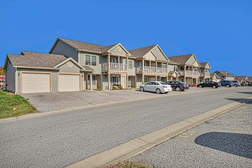 A row of houses with cars parked in front.