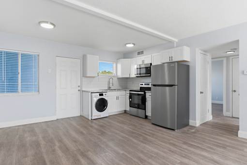 A modern kitchen with stainless steel appliances and wooden flooring.