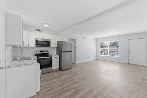 A kitchen with white appliances and wooden floors.