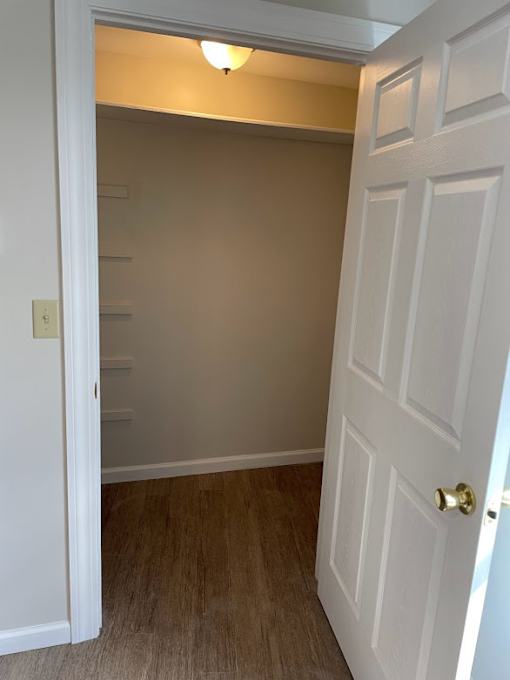 A white door with a gold handle is open to a room with a light on.