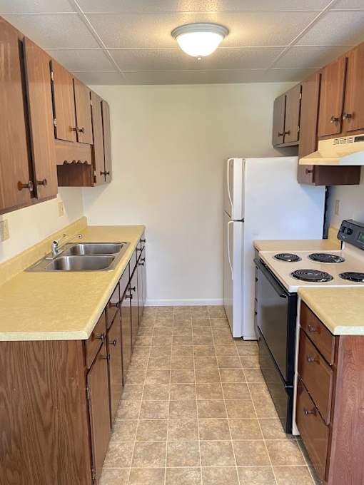 A kitchen with a white refrigerator and brown cabinets.