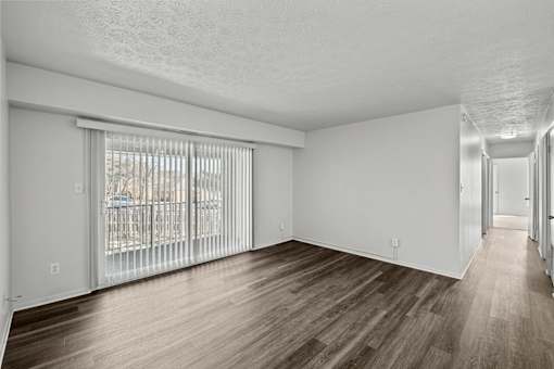 A spacious room with wooden flooring and white walls.