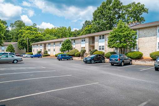A parking lot with cars and apartment buildings in the background.