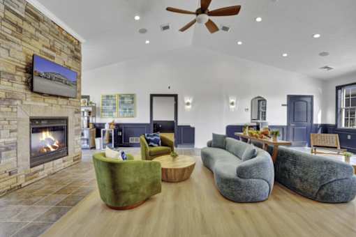 A living room with a stone fireplace and a flat screen TV mounted above it.