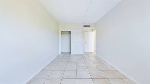 A long white hallway with a white door at the end.