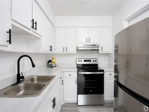 a kitchen with white cabinets and a sink and a stove