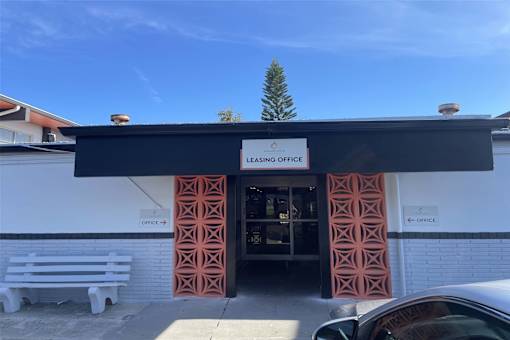 the front of the leasing office with a tree above the door