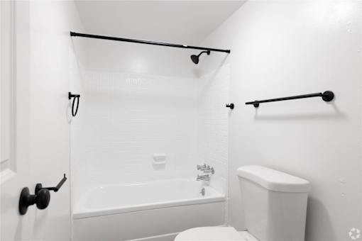 a white bathroom with a white toilet and a tub and a shower curtain