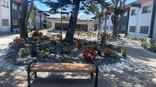 a bench in front of a courtyard with trees and plants