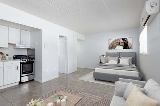 a white living room with a bed and a kitchen