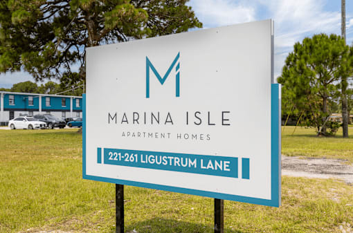a sign for marina isle apartment homes in front of a field