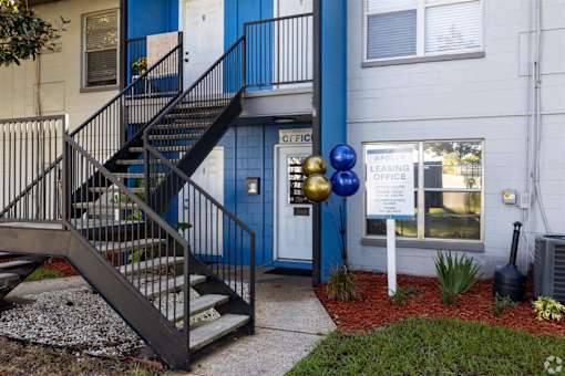 the front of a building with stairs and a sign in front of it