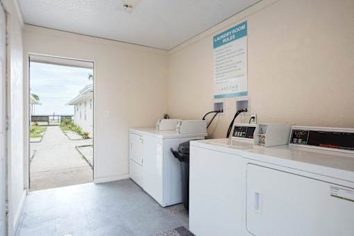 a laundry room with two washing machines and a door to the beach