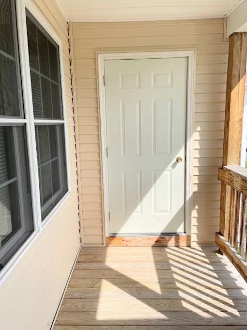 A white door is on the left side of a porch.