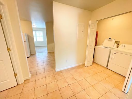 A kitchen area with a white fridge and a white door.