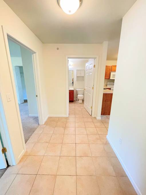 A hallway with tiled floors and white walls.