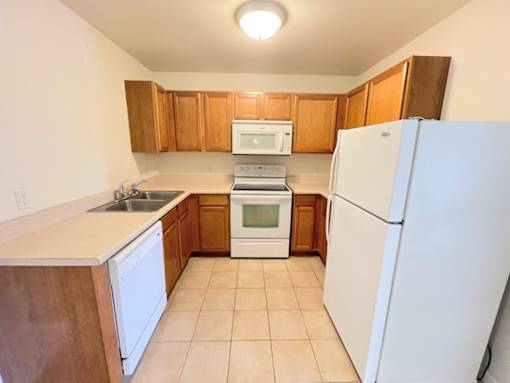 A kitchen with white appliances and wooden cabinets.