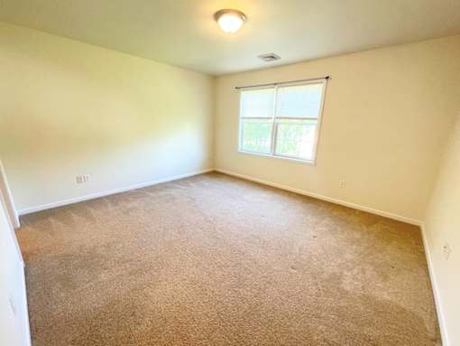 A room with a carpeted floor and a window.
