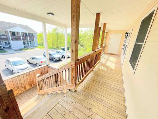 A balcony with a railing and a view of a parking lot and trees.