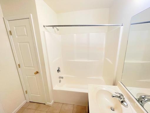 A white bathroom with a tub, sink, and mirror.