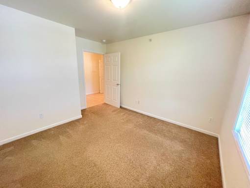 A room with a carpeted floor and a doorway leading to another room.