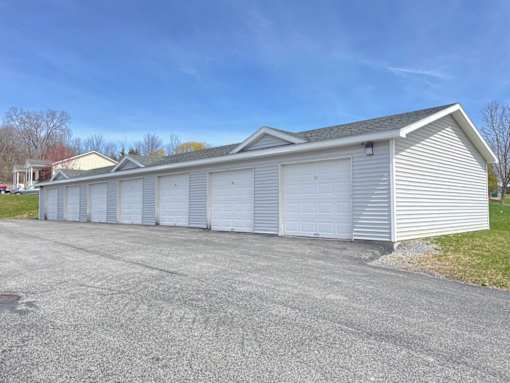 A long white garage with a grey roof and a grey driveway.