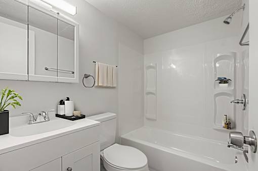 A white bathroom with a toilet, sink, and bathtub.