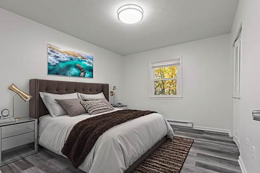 A bedroom with a large bed and a painting of a beach scene on the wall.
