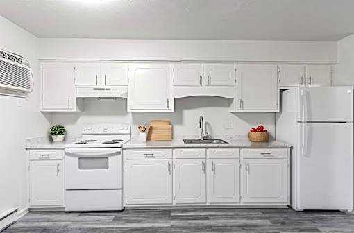 A white kitchen with a stove, oven, sink, and refrigerator.