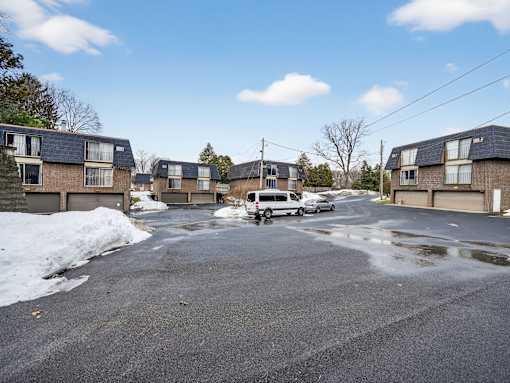 A residential street with houses on both sides and a van parked in the middle.
