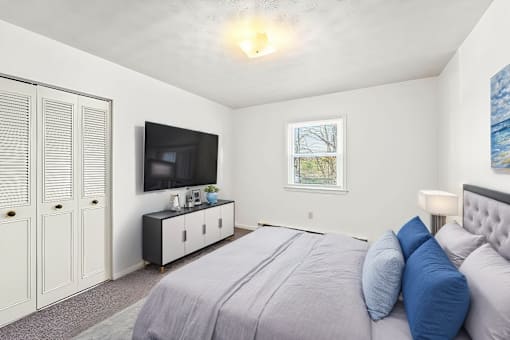 A bedroom with a large bed and a television on the wall.