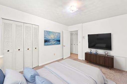 A bedroom with a bed, a cabinet, and a painting on the wall.