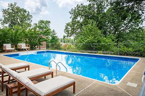 A pool with a blue tinted water and a white chair.