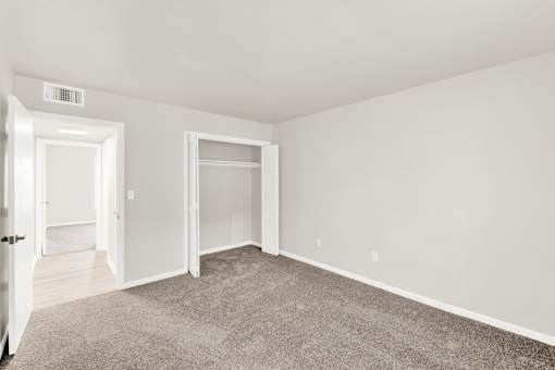 A room with a carpeted floor and two open doors.