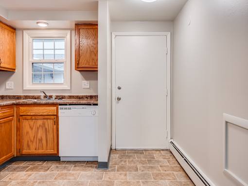 A kitchen with wooden cabinets and a white dishwasher.