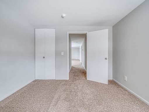 A hallway with carpeted flooring and white walls.