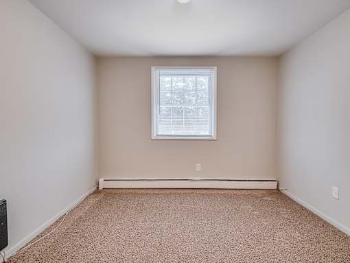 A room with a carpeted floor and a window.