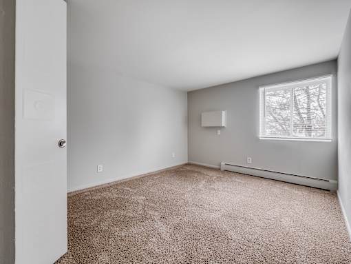 A room with a carpeted floor and a window.