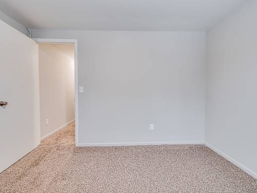 A room with a carpeted floor and a doorway leading to another room.