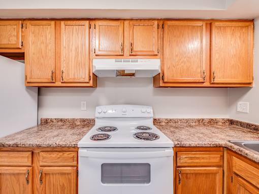 A kitchen with a white stove and wooden cabinets.
