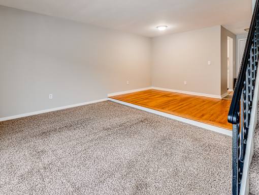 A room with a wooden floor and a carpeted area.