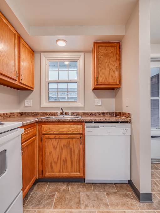 A kitchen with wooden cabinets and a white dishwasher.