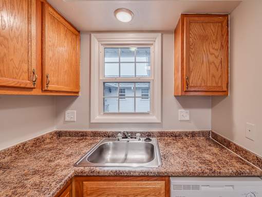 A kitchen with a granite countertop and wooden cabinets.