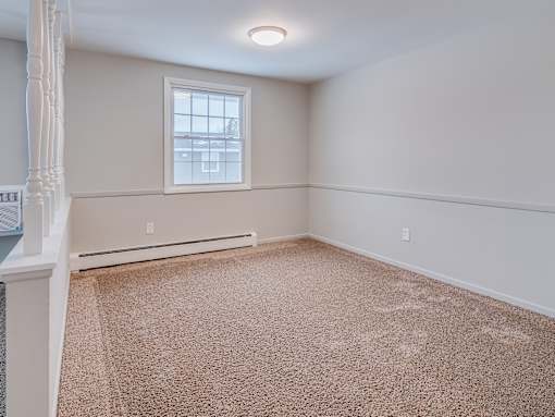 A room with a carpeted floor and a window.