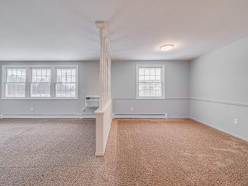 A room with a carpeted floor and a window.