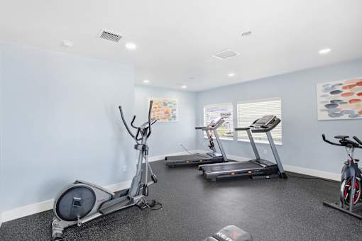 A room with a treadmill, elliptical trainer and a stationary bike.