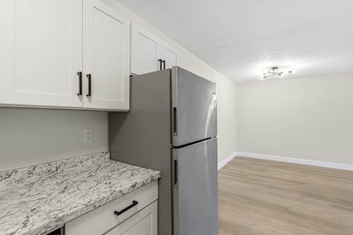 A kitchen with a marble countertop and a stainless steel refrigerator.